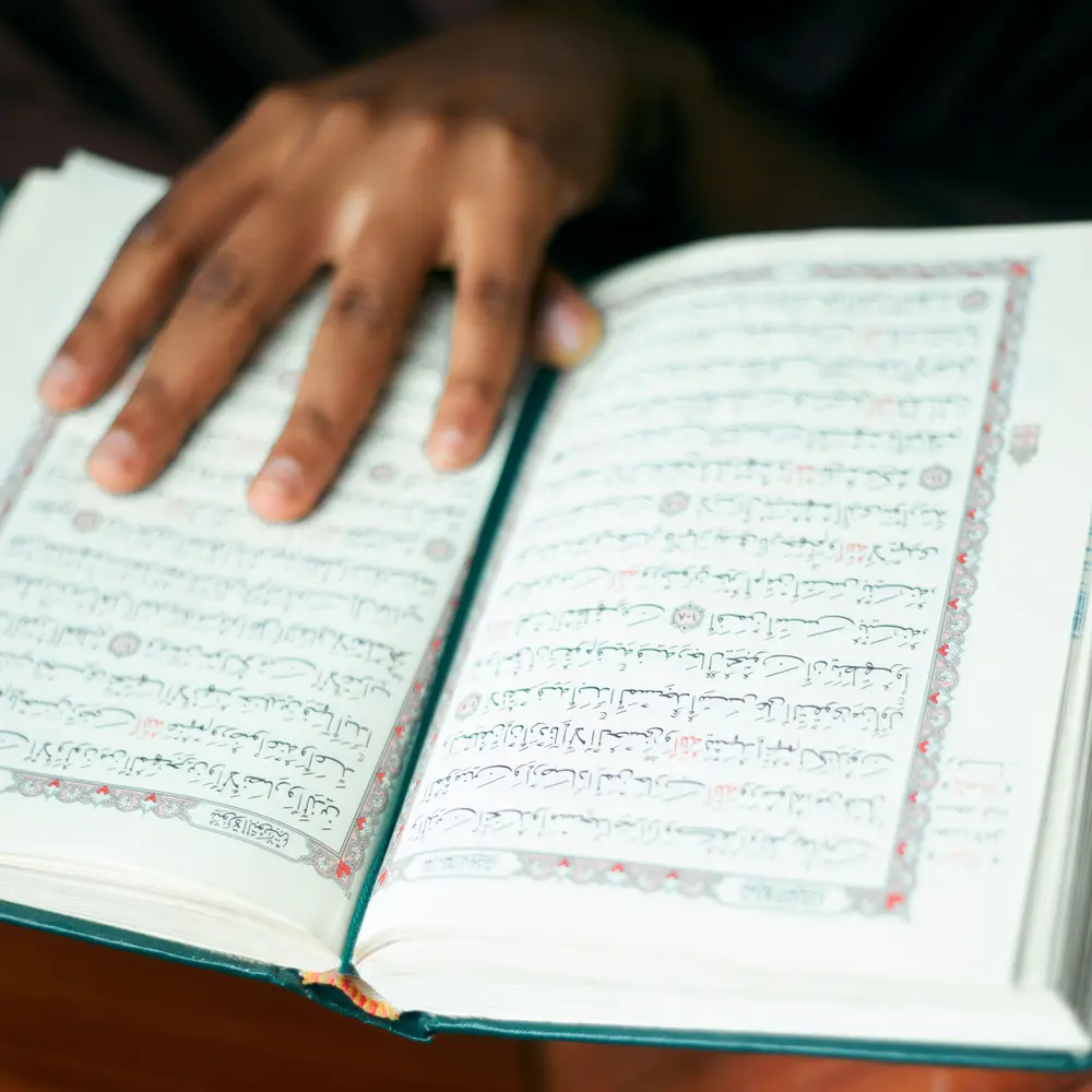 Une main posée sur les pages du Coran ouvert